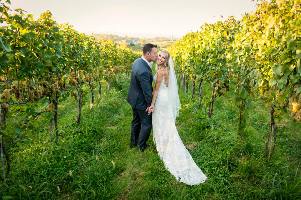 Wes and Kate kiss in the vineyard after their wedding ceremony at Blue Valley Vineyard