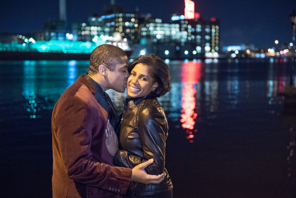 Ralph kissing Lauren in front of Domino Sugars during their engagement session at the Baltimore Inner Harbor