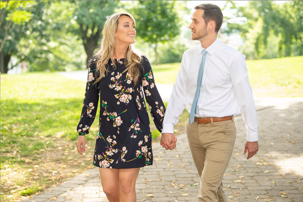 Meghan and Rob walking and smiling at Federal Hill Park during their engagement photography session at the Baltimore Inner Harbor
